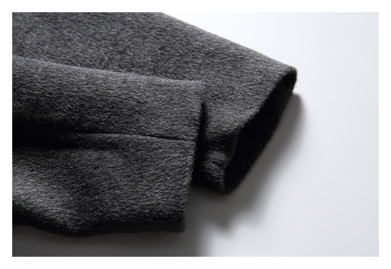 Close-up of a folded edge on a charcoal gray fuzzy coat, showing the thick fabric and seam.
