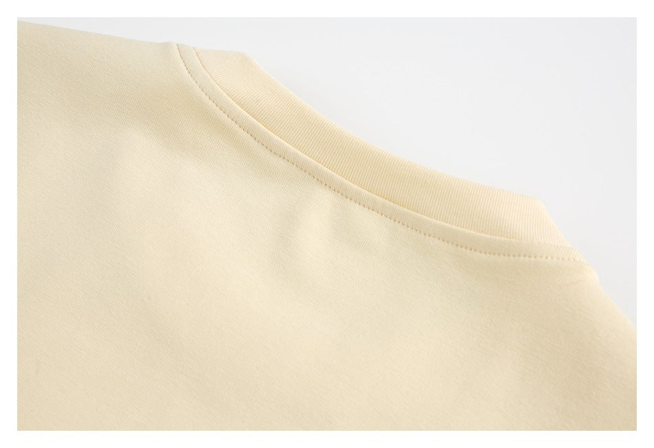 Close-up of the ribbed crew neckline and stitching on a pale cream garment.