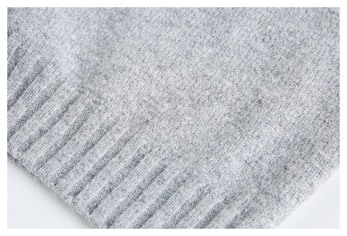 Close-up of light gray knit fabric with a wide ribbed edge.