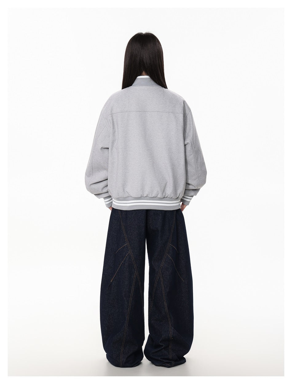 Rear view of a model wearing a light gray bomber jacket with striped ribbed cuffs and hem.