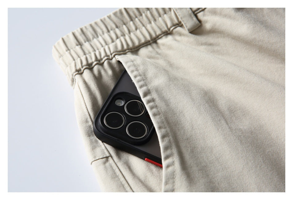 Close-up of a slanted side pocket in light beige trousers, with a phone tucked inside.