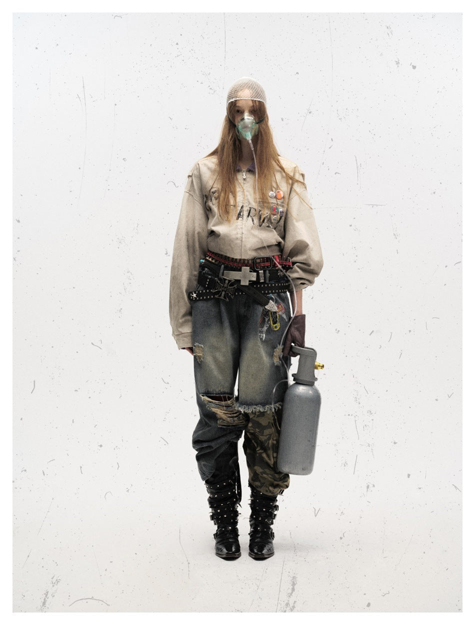 Model standing in a washed off-white jacket with chest badges, layered with distressed jeans, belts and black boots