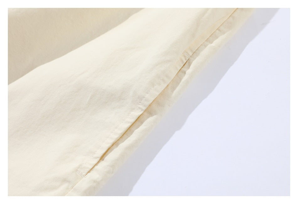 Close-up of a stitched side seam and edge on an off-white garment.