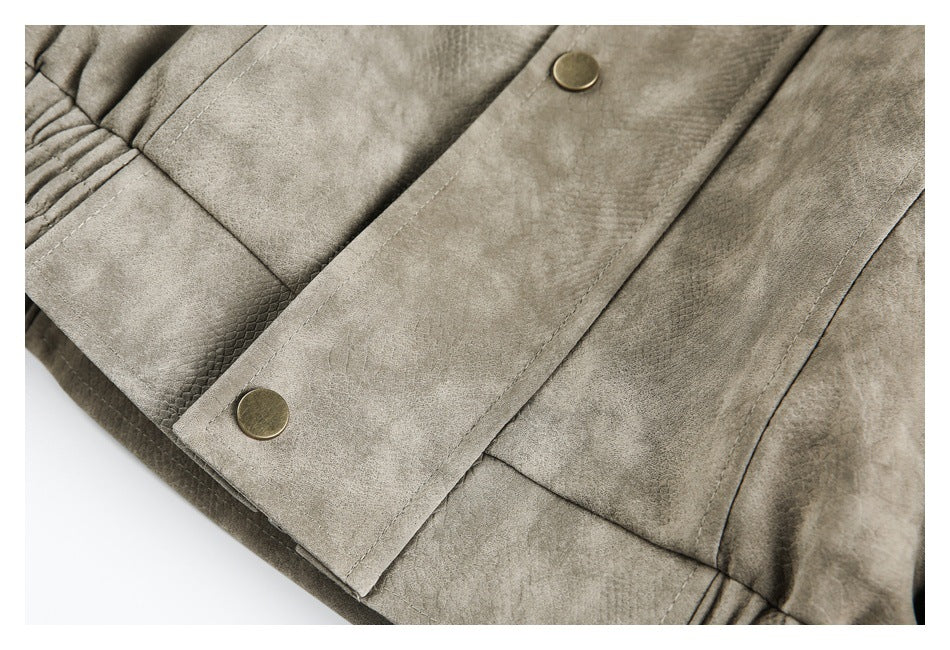 Close-up of a taupe-gray jacket front placket with two round brass-tone snaps and stitched panels.