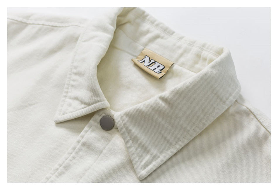 Close-up of an off-white shirt-jacket collar, gray snap button, and tan neck label.