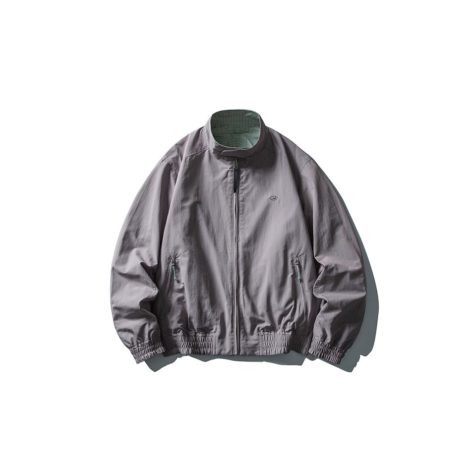 Front view of a muted gray-purple jacket with a stand collar, full-length zipper, two zip pockets, and elasticated trim.