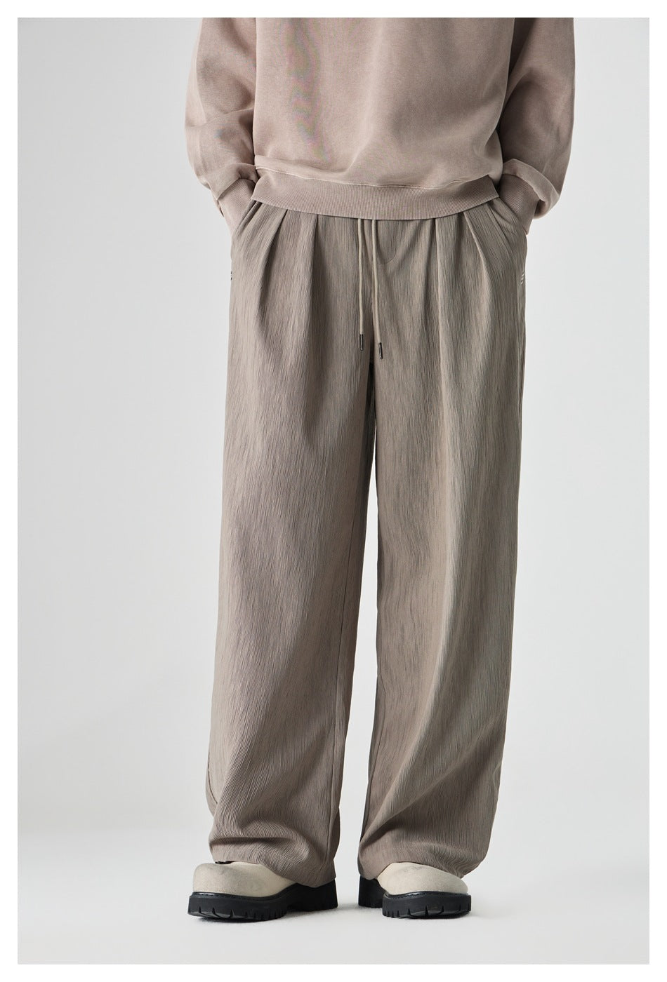 Model wearing taupe-gray wide-leg drawstring pants with a subtle crinkled texture, shown from the front.