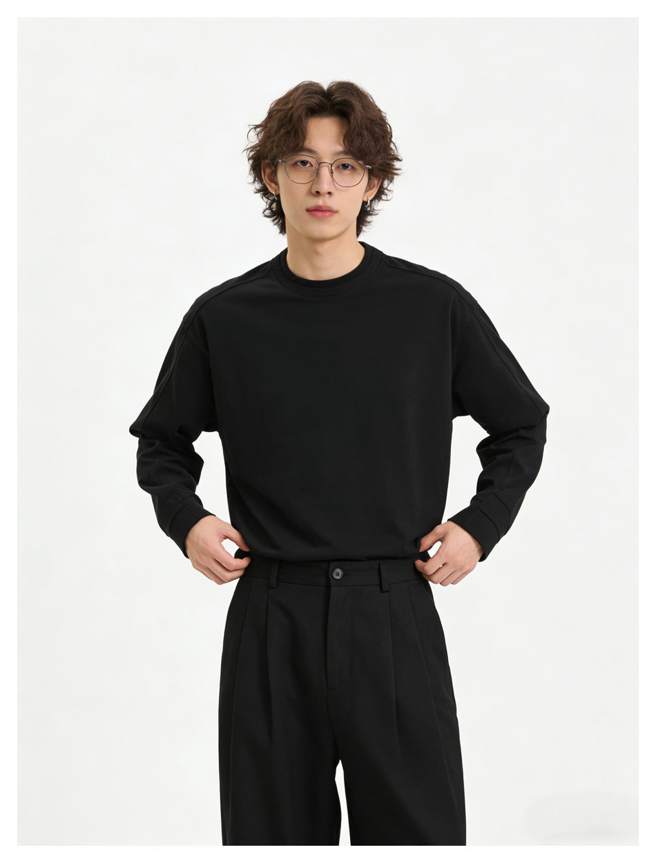 Model wearing a plain black crewneck sweatshirt and black trousers, shown from the front.