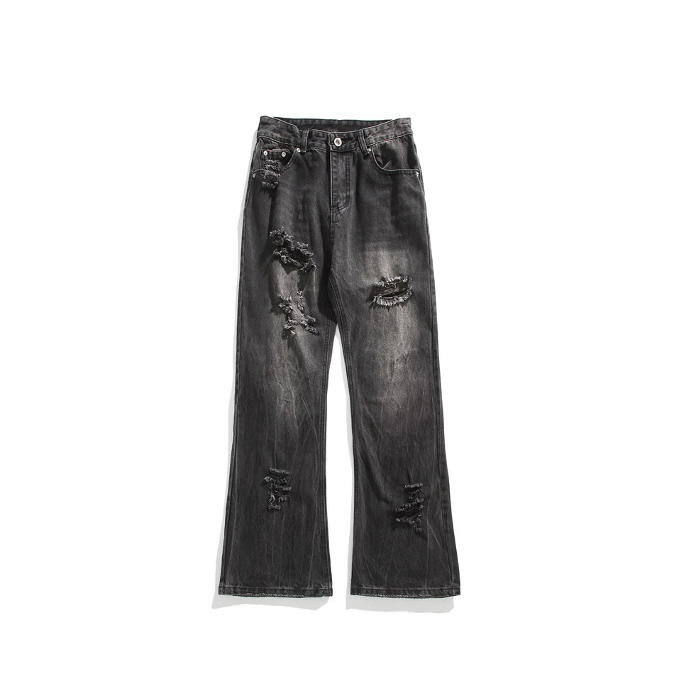 Front view of washed black distressed flared jeans with frayed rips on the thighs and knees