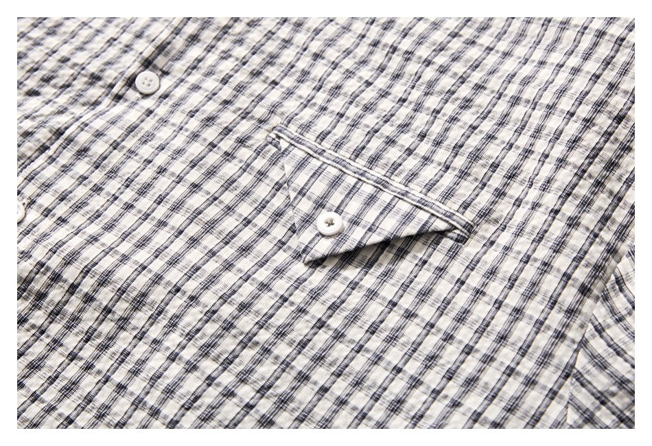 Close-up of a buttoned chest pocket on a cream shirt with a black and gray plaid pattern.