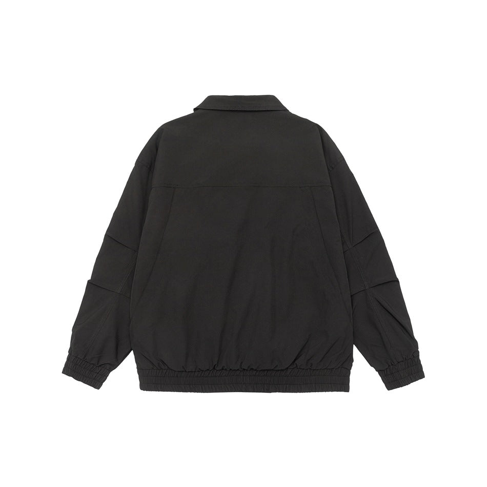 Back view of a black collared jacket with long sleeves, seam detailing, and elastic cuffs and hem on white.