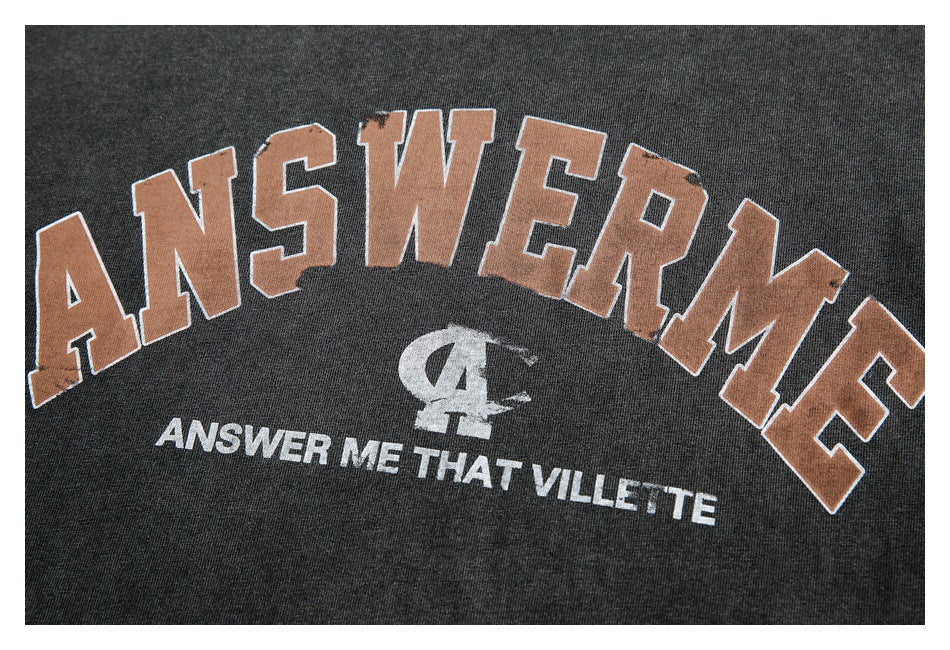 Close-up of a charcoal sweatshirt graphic with large tan lettering and smaller white text.
