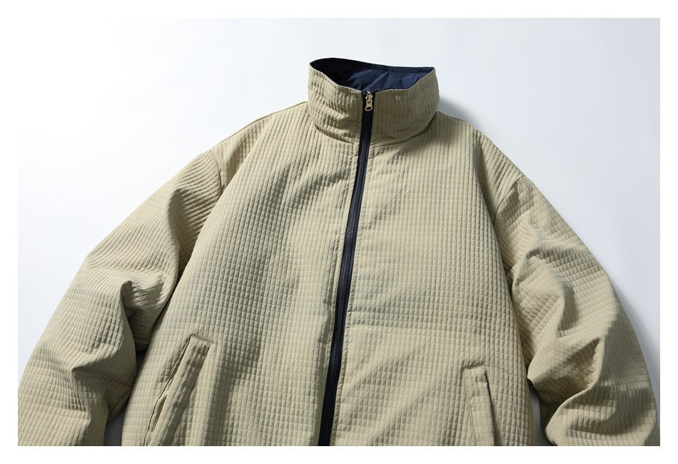 Front view of a light khaki quilted jacket with a high collar, navy zipper, and slanted pockets.