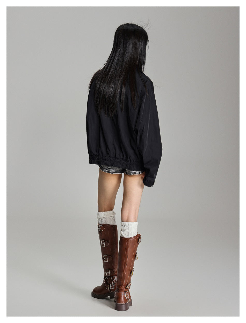Rear view of a model wearing a black oversized jacket with a gathered hem and long sleeves.