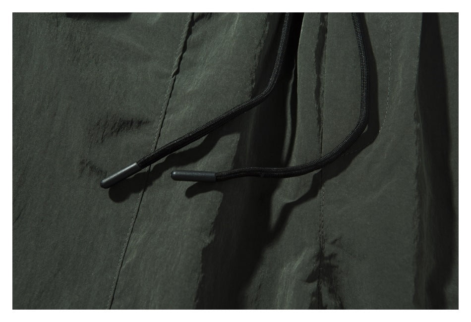 Close-up of the black drawcord ends against the dark olive shorts.