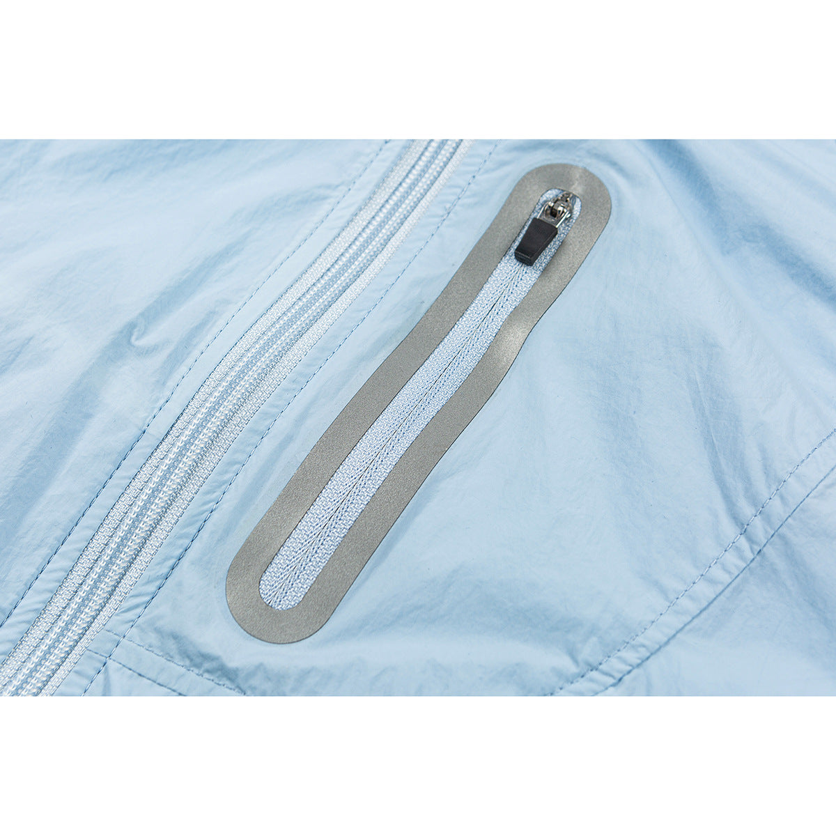 Close-up of a light blue jacket showing a zipper and a narrow gray-trimmed zip pocket.