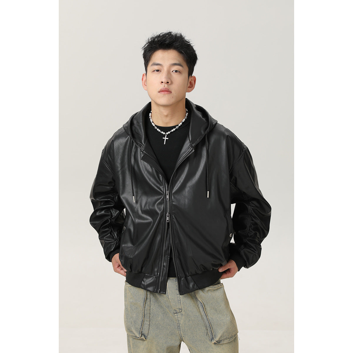 Model wearing a black hooded zip jacket with drawstrings and ribbed cuffs, paired with loose faded cargo jeans.