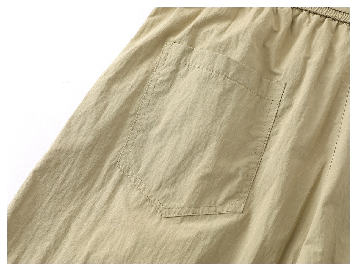 Close-up of a large stitched patch pocket on light khaki pants.