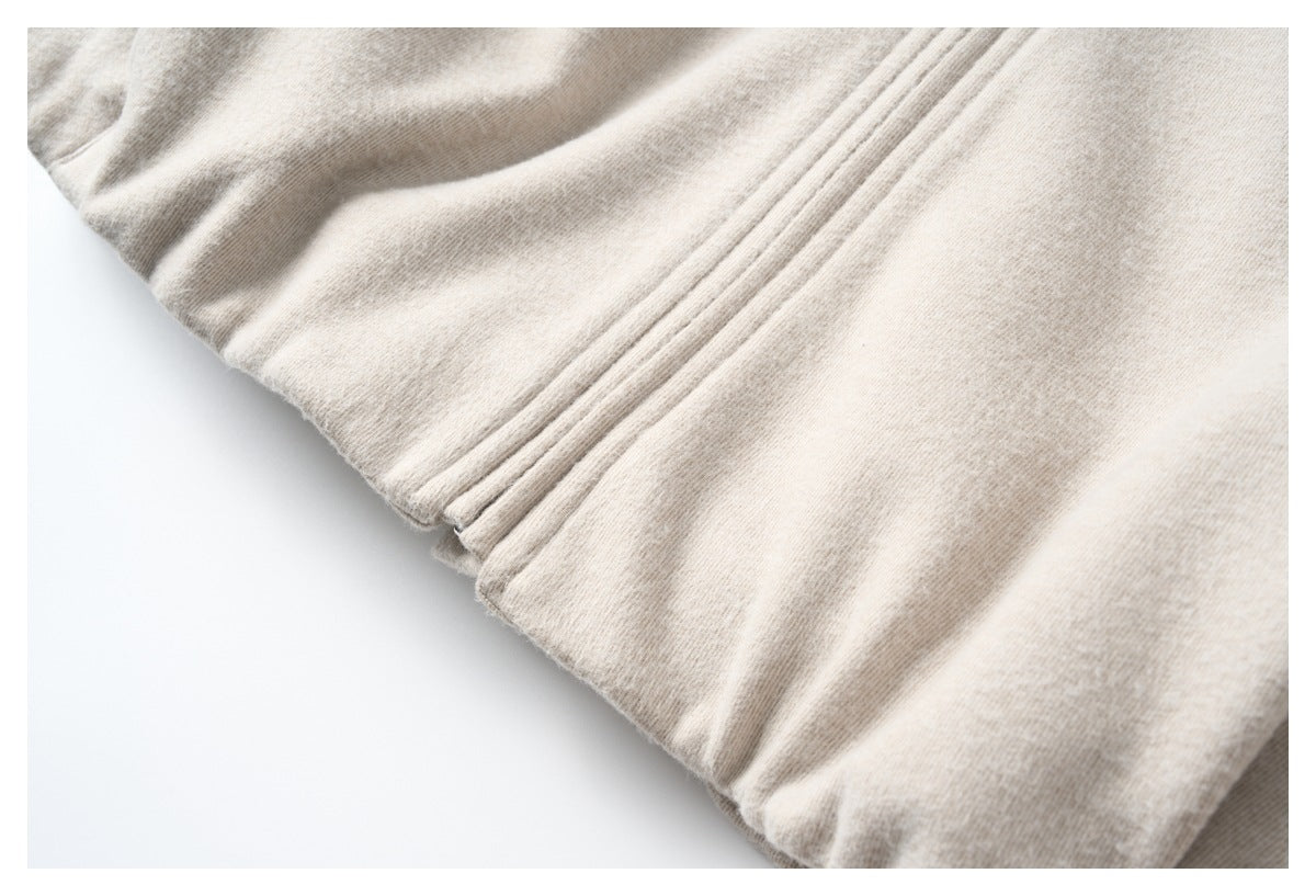 Close-up of a light beige garment hem with parallel stitched folds.