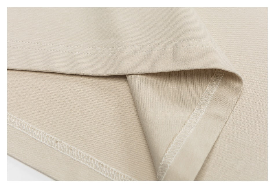 Close-up of the beige T-shirt hem, showing folded fabric and overlocked inner stitching.