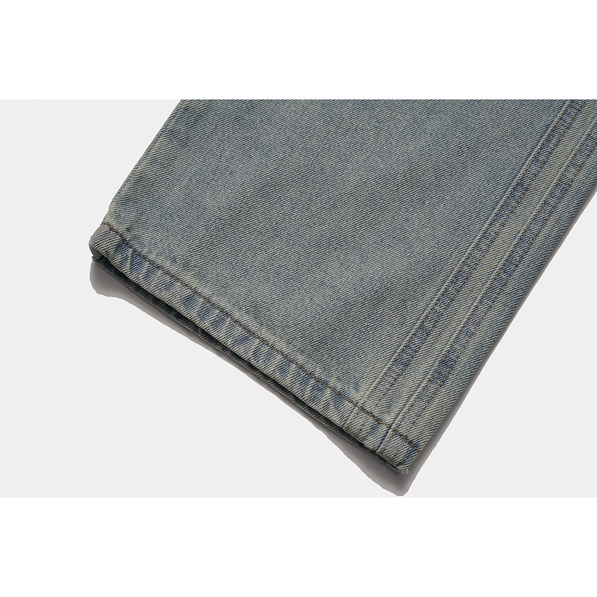 Close-up of a light-wash jeans leg showing the stitched hem and side seam.