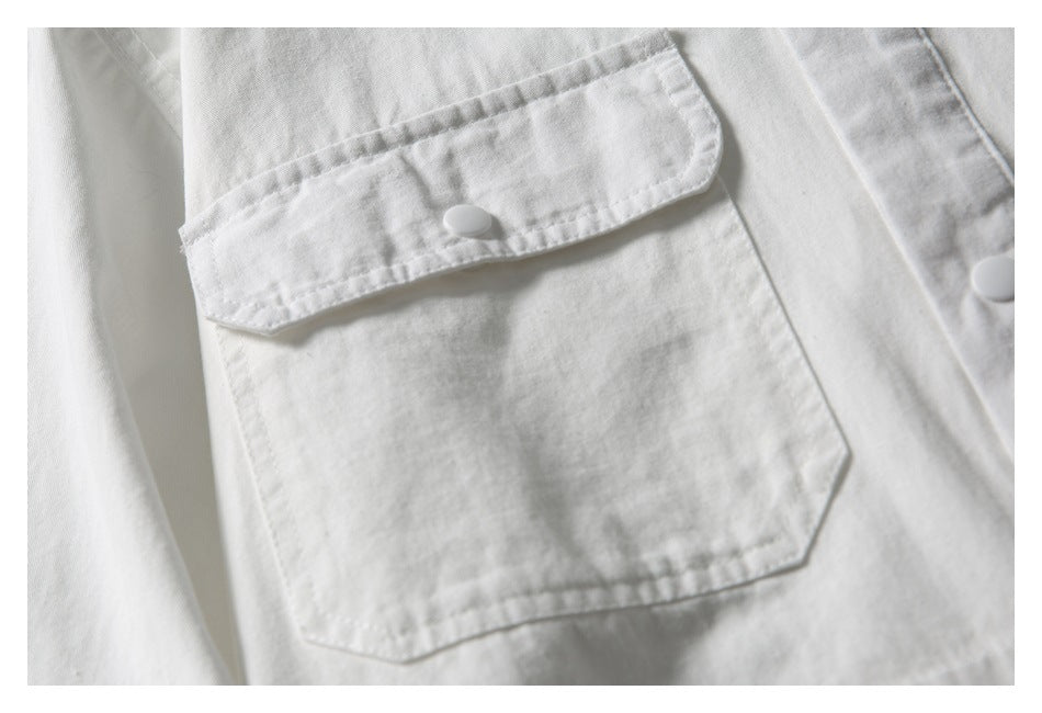 Close-up of a white shirt’s flap chest pocket with a snap button.