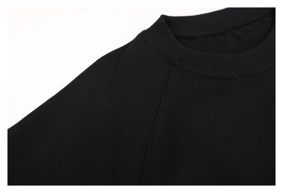 Close-up of the black sweatshirt's crew neck and raglan shoulder seam.