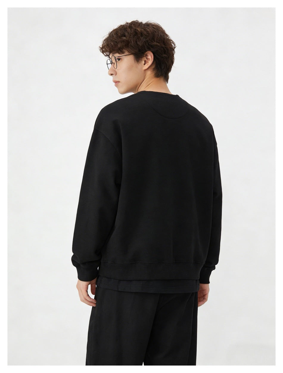 Back view of a model wearing a plain black sweatshirt with ribbed cuffs and hem.