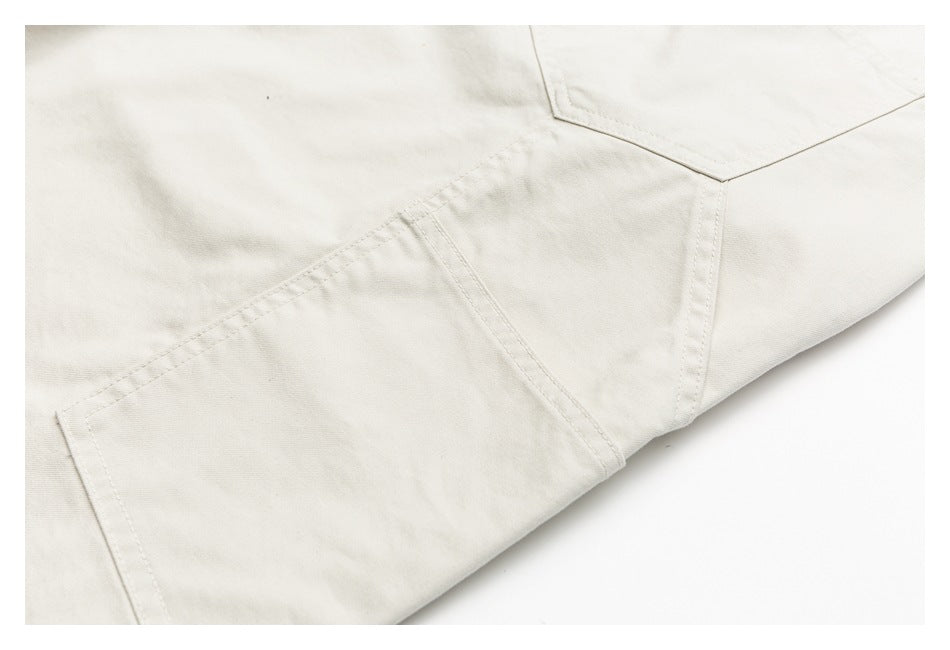 Close-up of ivory trousers showing a pocket edge, panel seams and stitching.