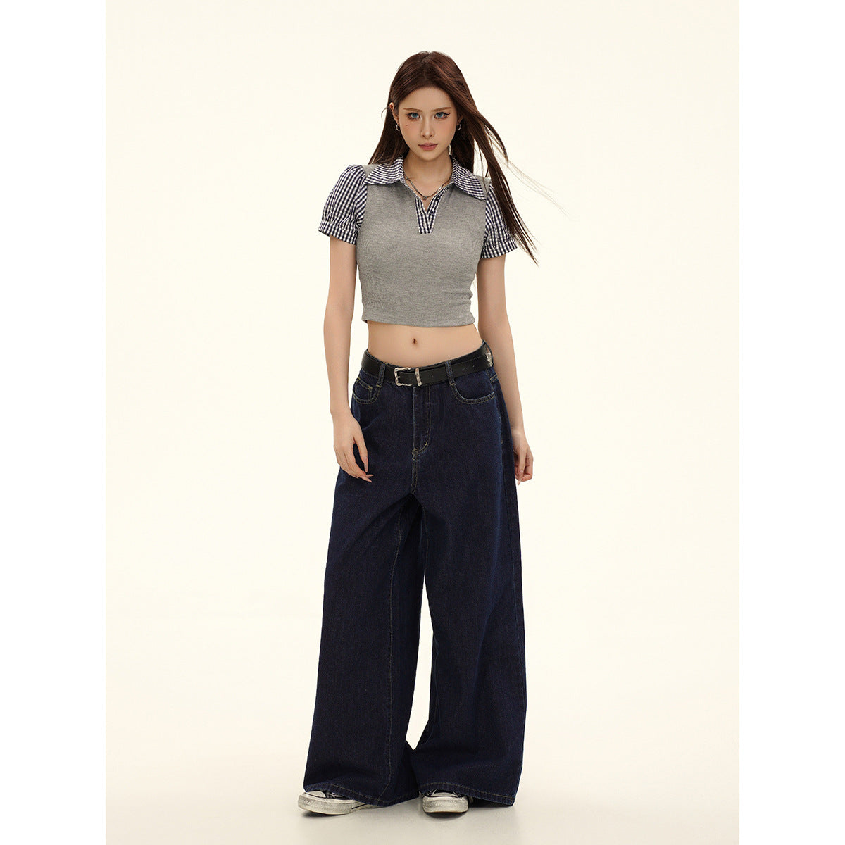 Full-length front view of a model wearing a gray cropped top with gingham collar and puff sleeves, and dark wide-leg jeans.