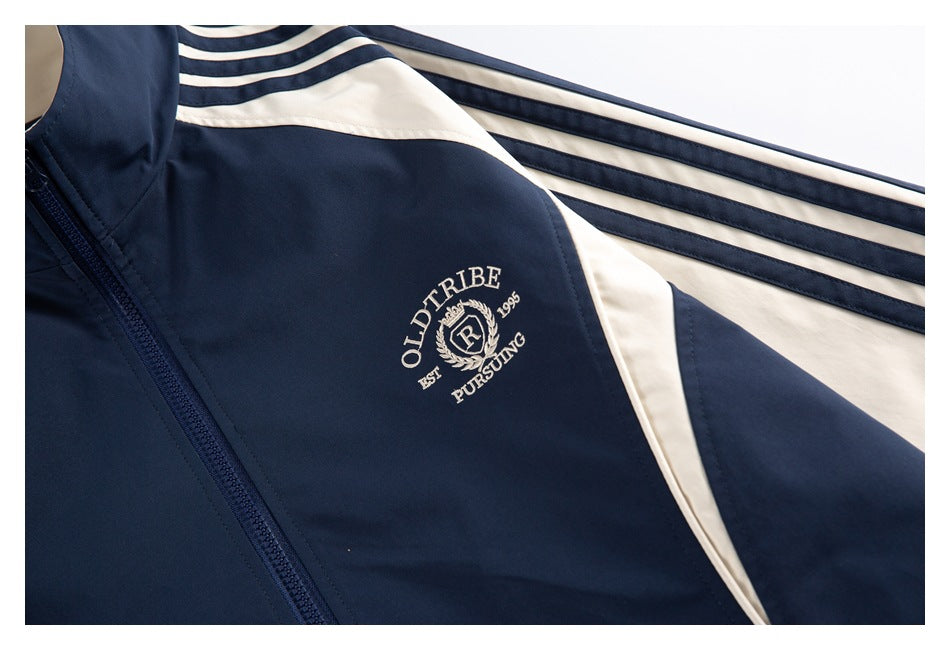 Close-up of the navy jacket's cream embroidered chest crest and cream-and-navy sleeve stripes.