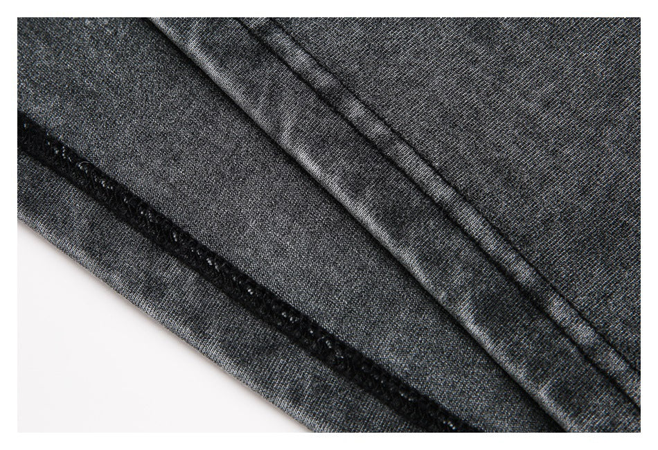 Close-up of charcoal heathered fabric showing a black overlocked seam and stitched folded edge.