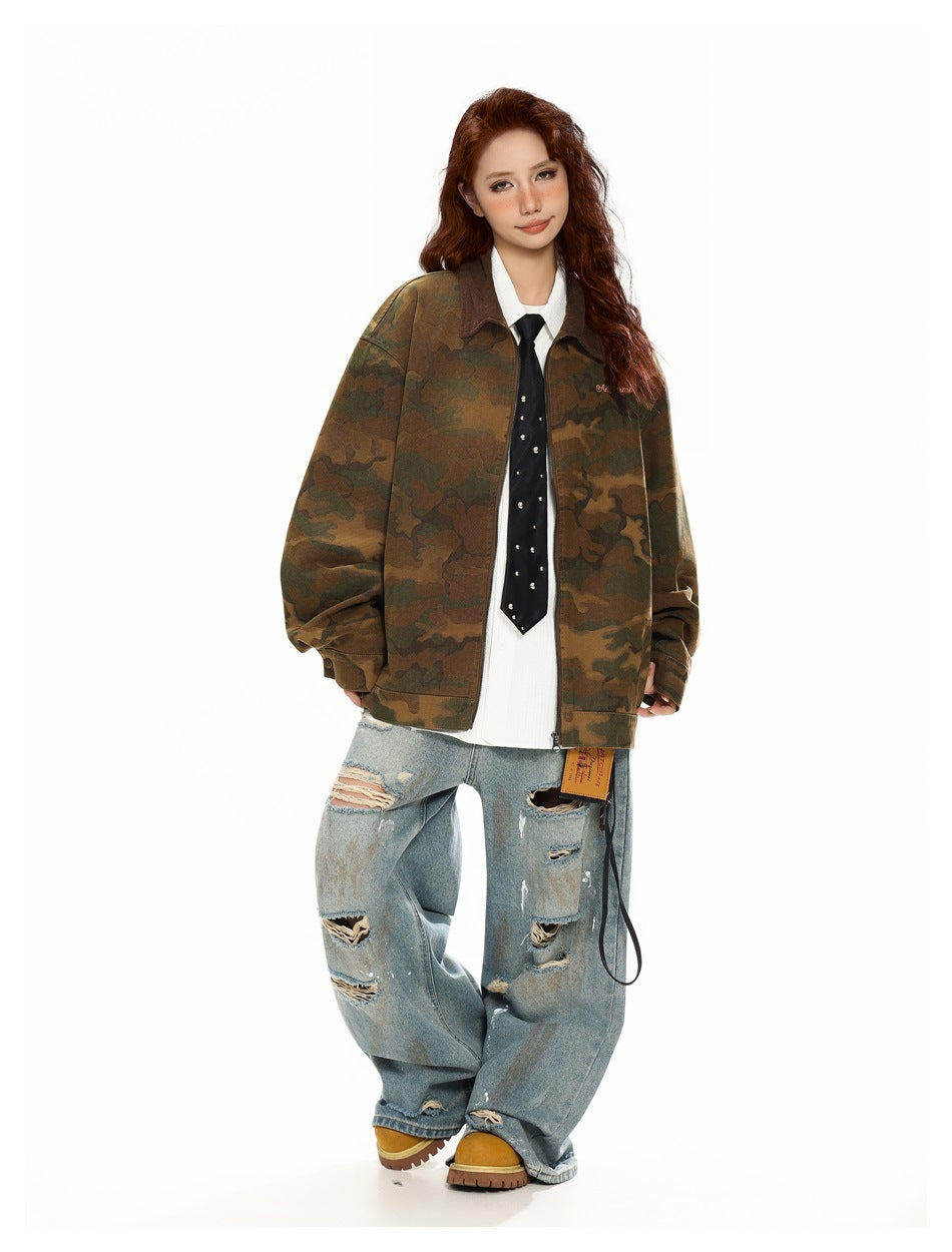Full-length model wearing an oversized brown and olive camouflage zip jacket with distressed light-wash jeans and boots.