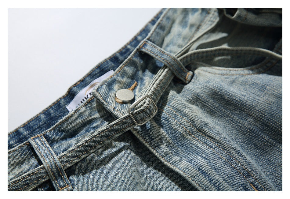 Close-up of faded blue jeans showing the waistband, belt loops, metal button, and adjustable buckle strap.
