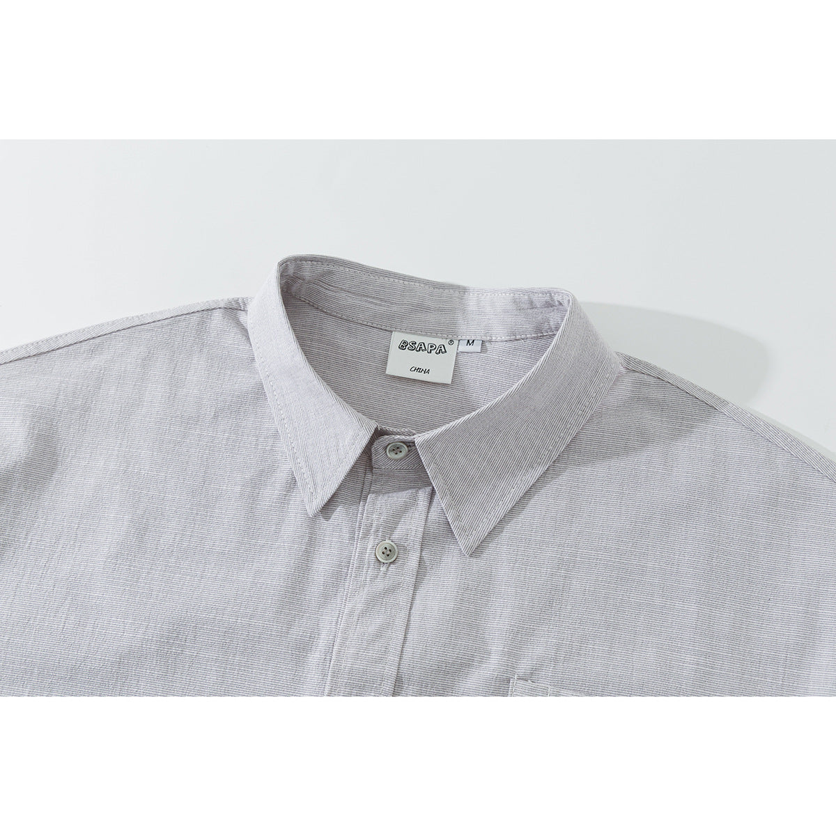 Close-up of a light gray fine-striped short-sleeve shirt showing its pointed collar, buttons and neck label.