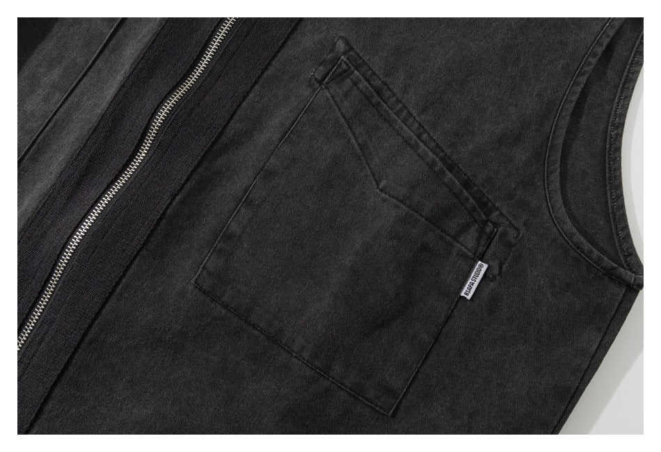 Close-up of a charcoal garment's angled front pocket, armhole edge, and silver zipper.