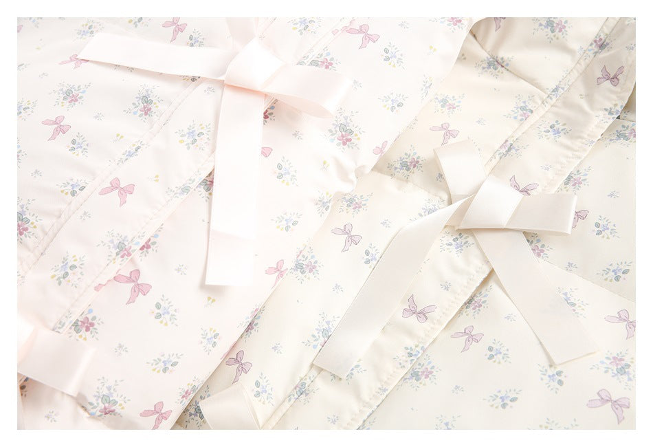 Close-up of overlapping pale pink and ivory printed garments with wide pale pink ribbon ties.