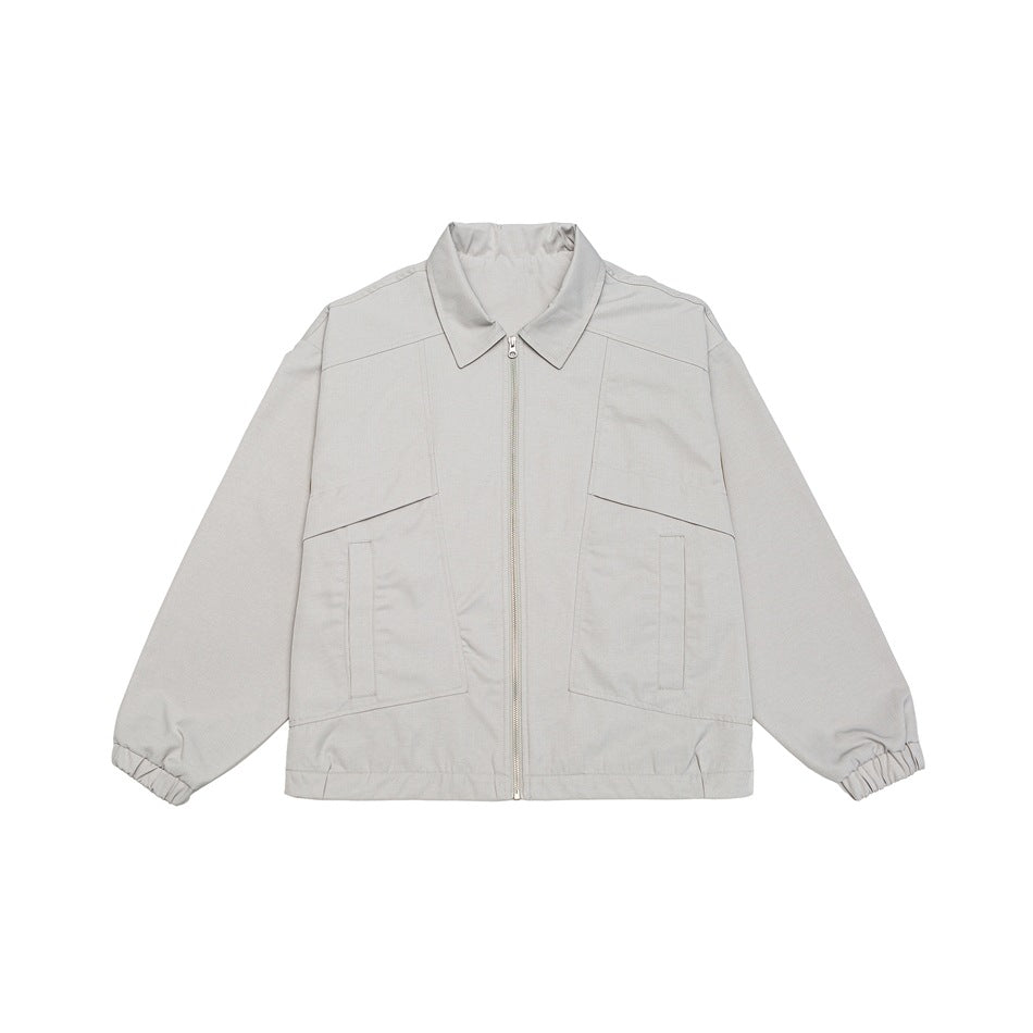 Beige zip-front collared jacket with large paneled front pockets and elastic cuffs, flat lay on white