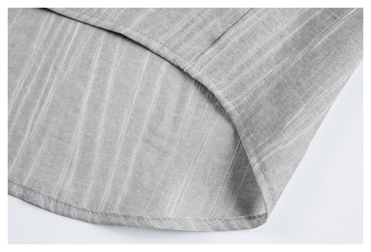 Close-up of gray subtly striped fabric showing a curved stitched seam and finished hem.