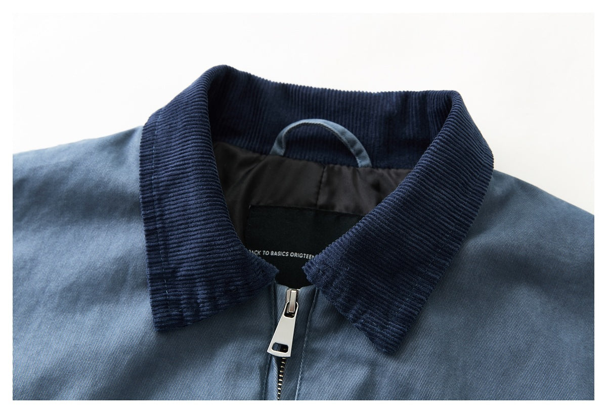 Close-up of a blue jacket's dark ribbed collar, neck label, and silver front zipper.