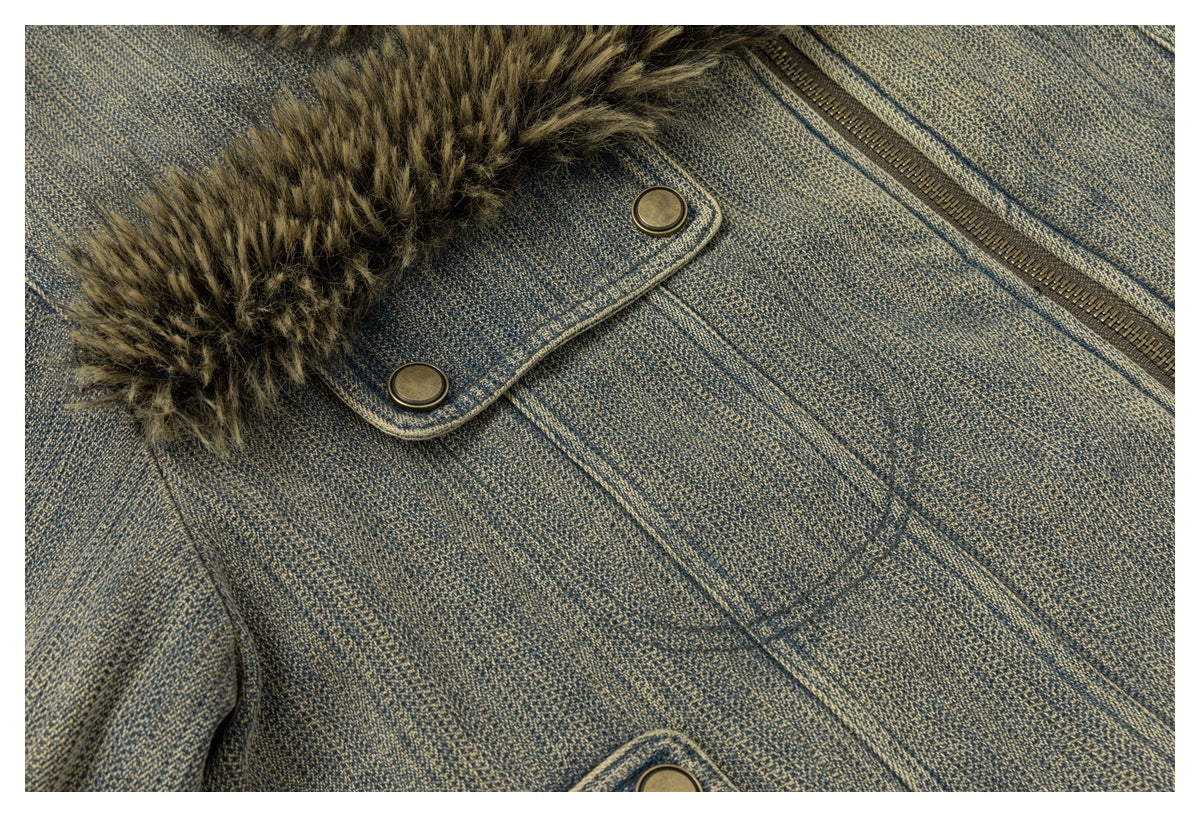 Close-up of a blue-gray jacket front showing brown faux-fur trim, a brass-tone zipper and snap-fastened flap.
