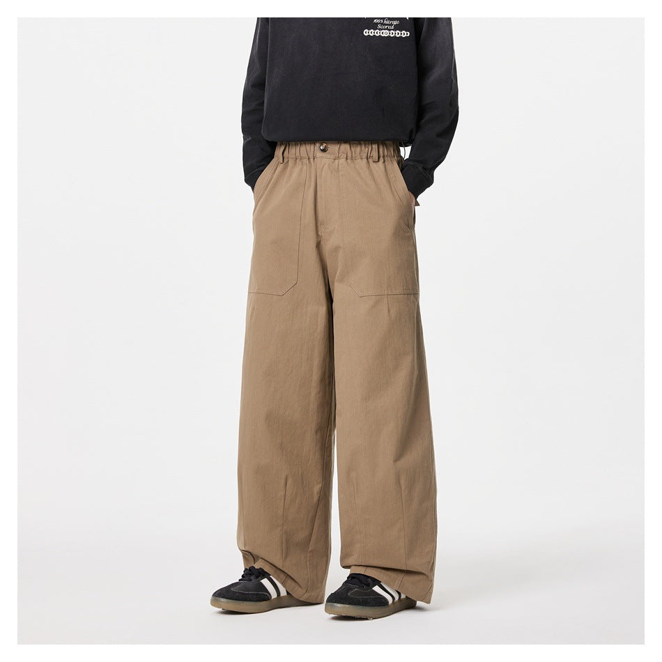 Front view of a model wearing tan wide-leg trousers with an elasticated waist and large front patch pockets.