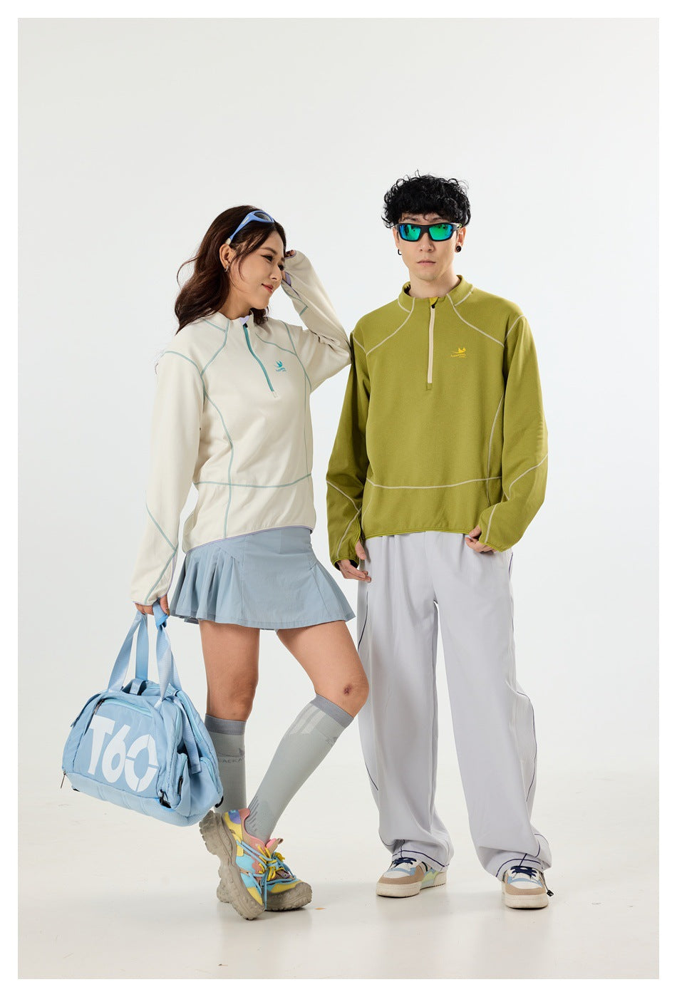 Two models wear off-white and olive quarter-zip pullovers with pale contrast stitching.
