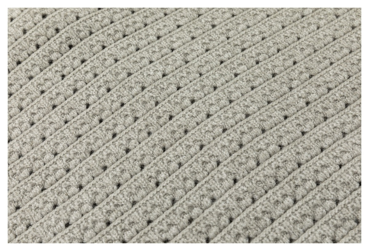 Close-up showing raised parallel ribs and small open stitches in light gray knit fabric.