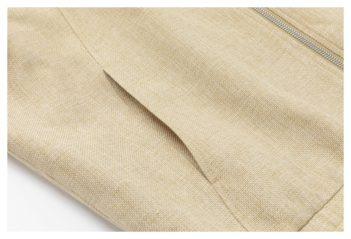 Close-up of a beige woven jacket showing a diagonal seam and part of a metal zipper.
