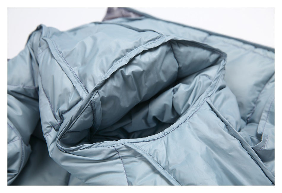 Close-up of the light blue-gray quilted garment showing its folded hood and stitched seams.