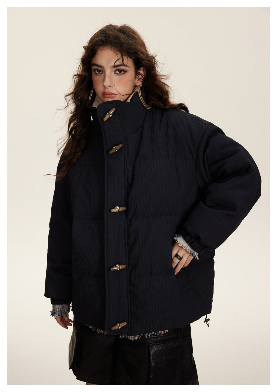 Front view of a model in a dark navy padded jacket with wooden toggles, high collar, and roomy sleeves.