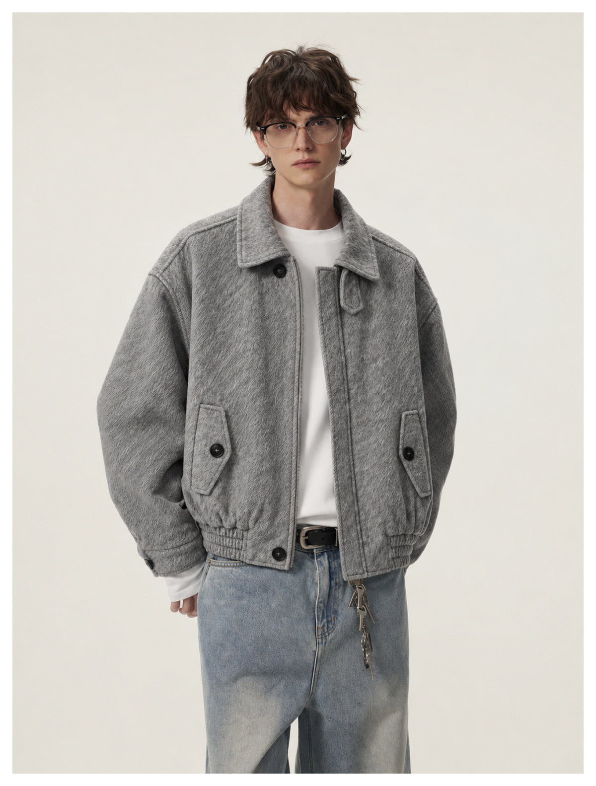 Model wearing a gray textured bomber-style jacket with a wide collar, buttoned pockets and ribbed hem.