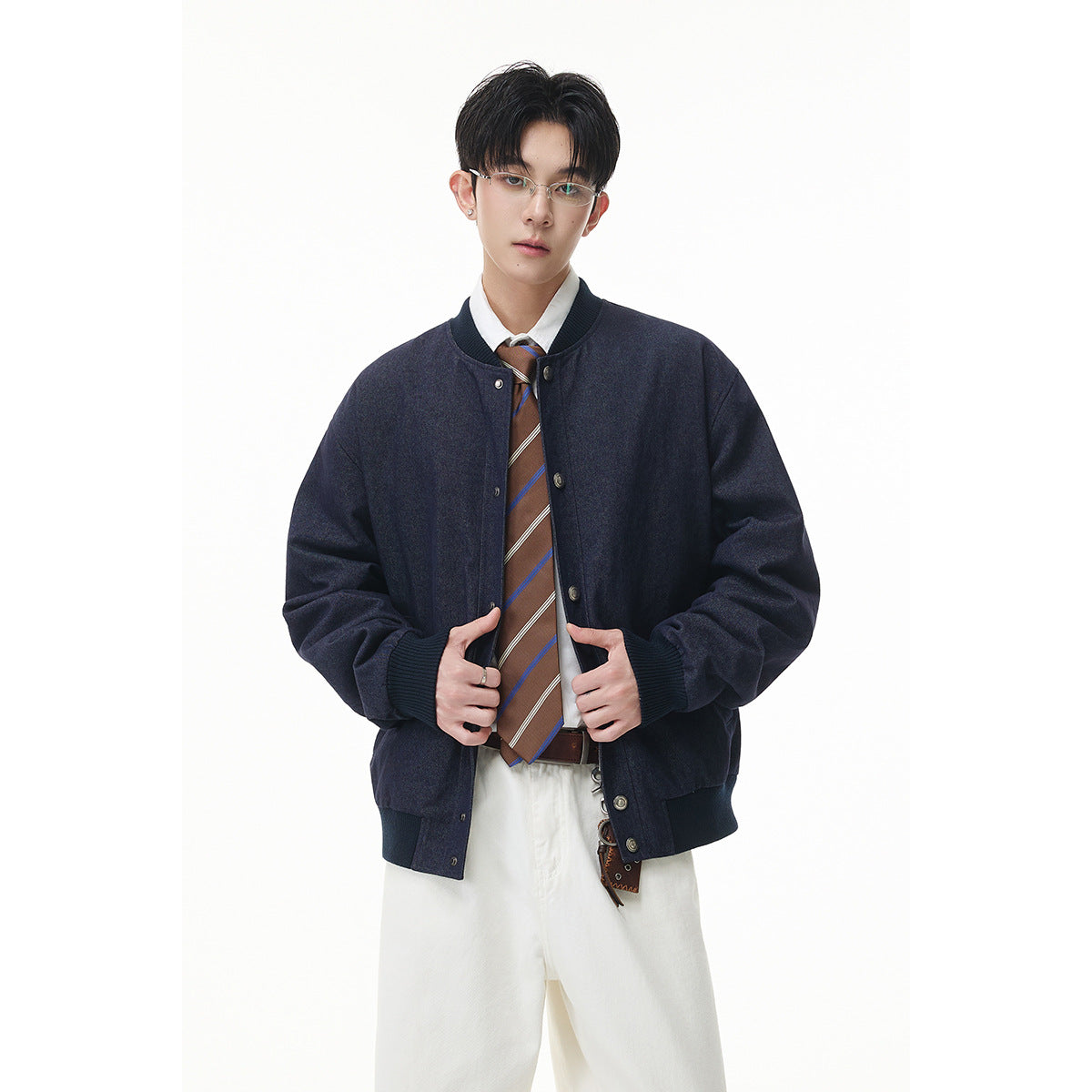 Model wearing an open dark navy bomber jacket over a white shirt and brown striped tie.
