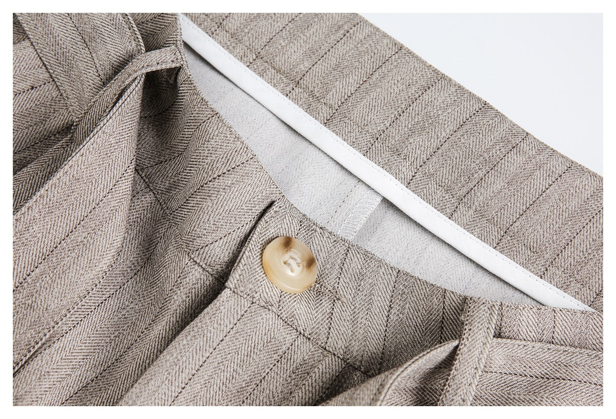 Close-up of the trouser waistband interior, showing a button, belt loops and striped fabric.